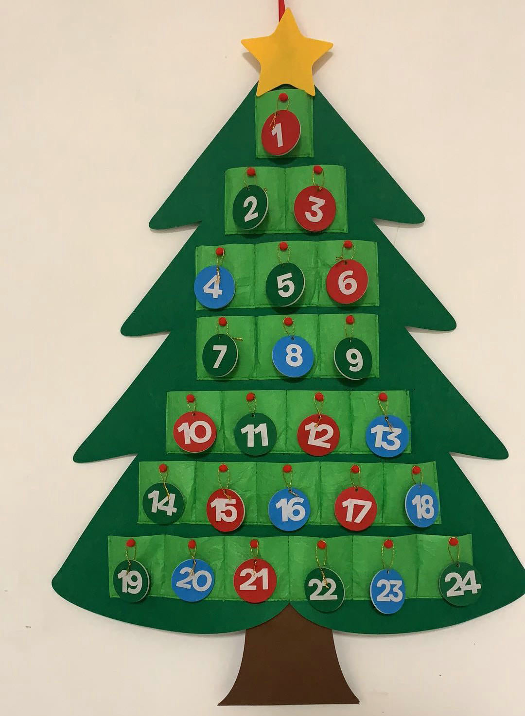 One green felt Christmas tree advent calendar with 24 pockets and numbered hanging discs