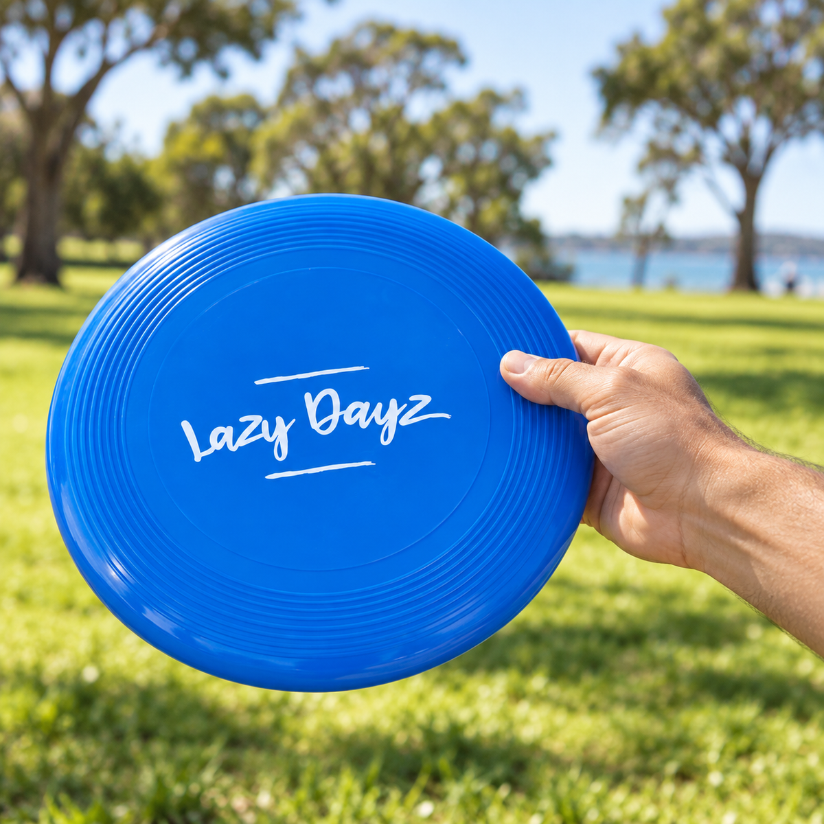Illustrative lifestyle view of the blue Lazy Dayz flying disc held ready for outdoor play