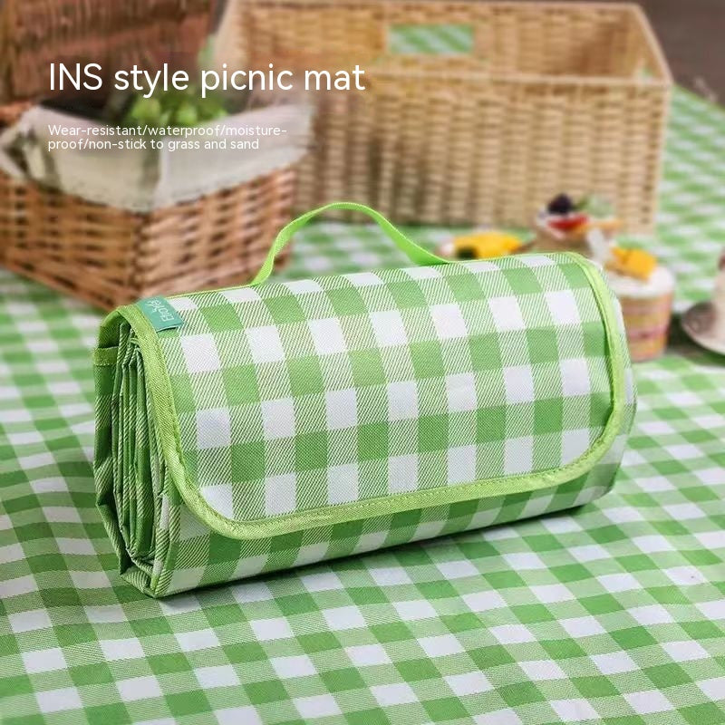 Green checked picnic mat shown folded beside a picnic basket